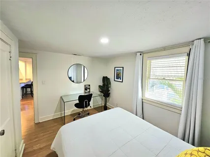 a bedroom with a bed a mirror on table and a window