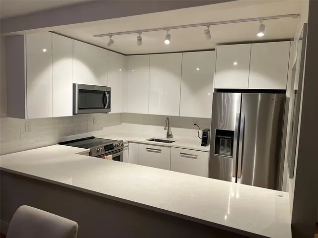 a kitchen with a sink a refrigerator and a stove top oven
