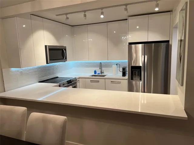a kitchen with stainless steel appliances a refrigerator sink and microwave