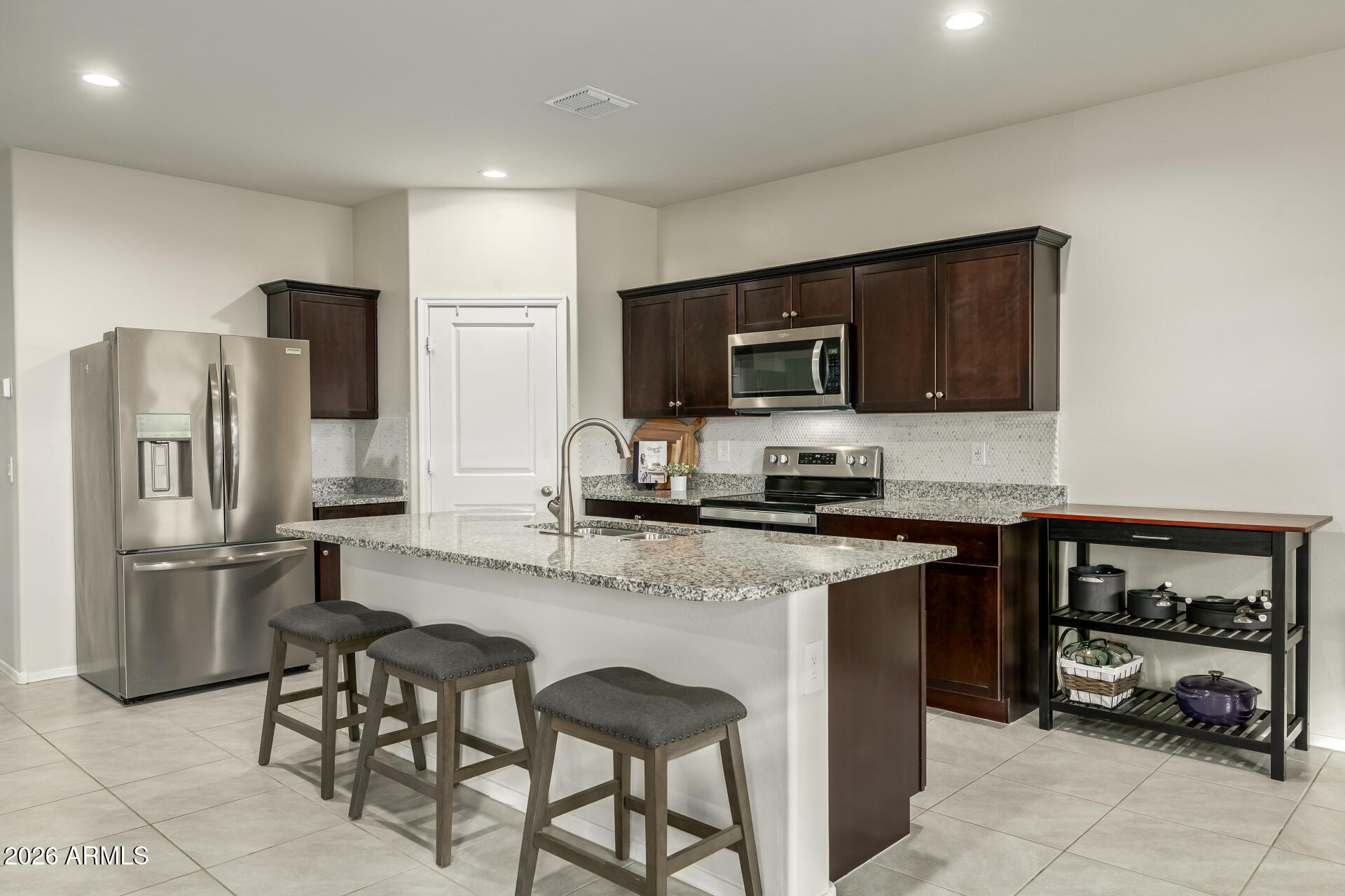 9471 Greenhouse Road Florence, AZ 85132 - Photo 4 of 22 a kitchen with stainless steel appliances granite countertop a stove top oven a refrigerator a sink and chairs