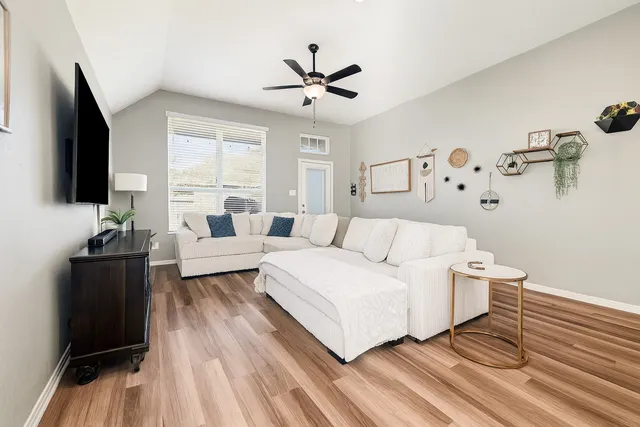 a living room with a bed furniture flat screen tv and window