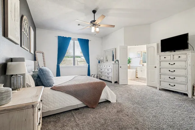 a bedroom with a bed and a flat tv screen on dresser