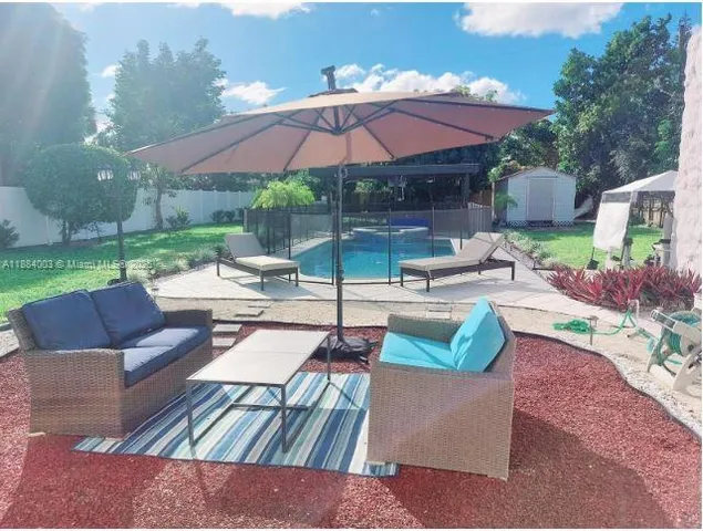 a patio with tables and chairs under an umbrella