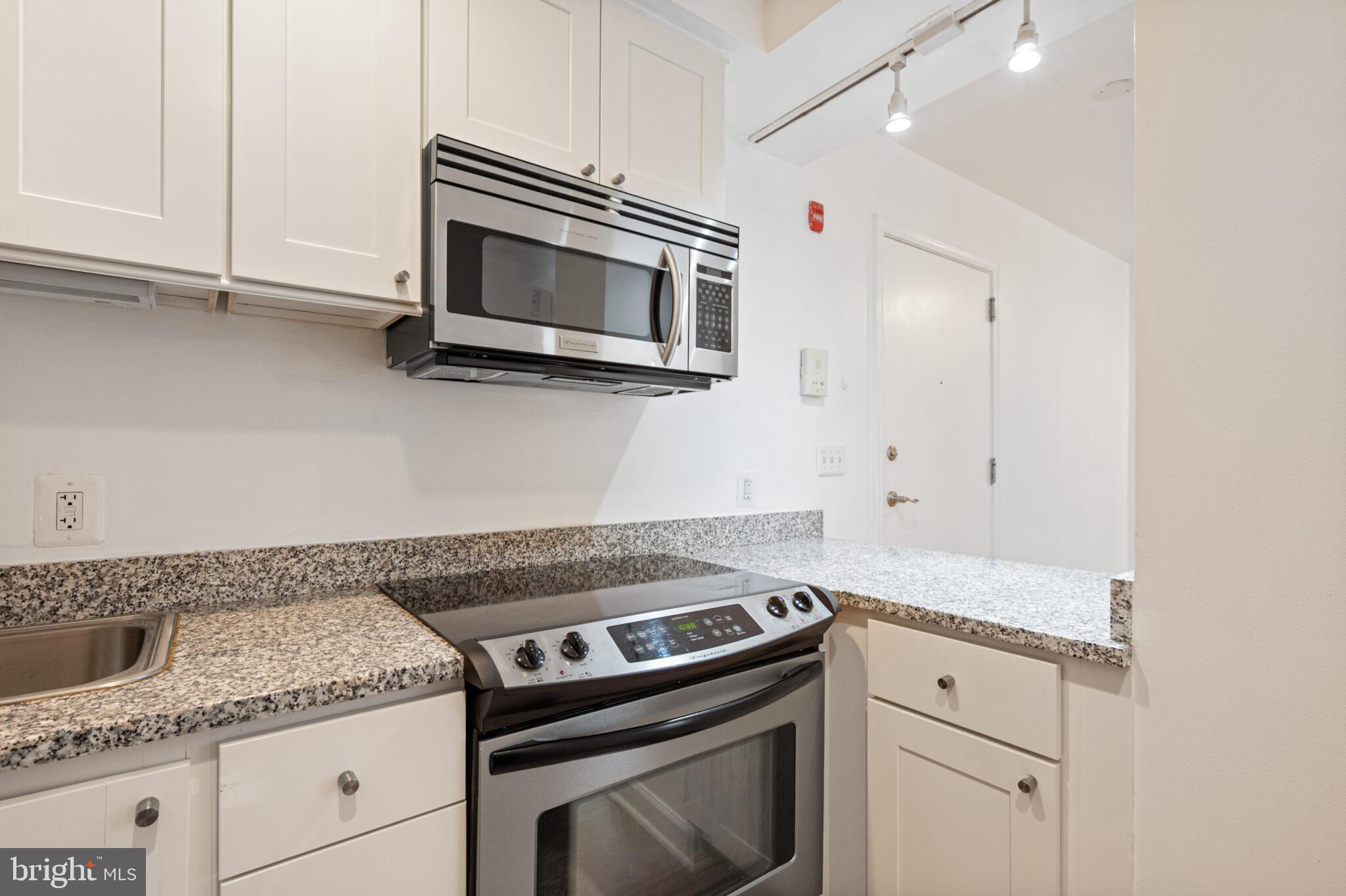 1314 Massachusetts Avenue Northwest, Unit 608 Washington, DC 20005 - Photo 12 of 40 a kitchen with granite countertop white cabinets and stainless steel appliances