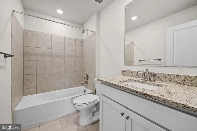 a bathroom with a granite countertop sink a toilet and bathtub