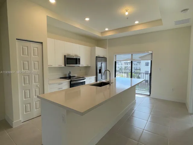 a large kitchen with a large counter top stainless steel appliances and cabinets