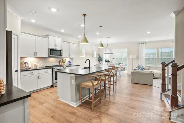 a large kitchen with stainless steel appliances kitchen island granite countertop a large island in the center