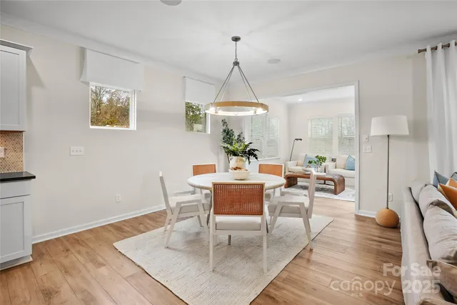 a dining room with wooden floor a chandelier a glass table and chairs