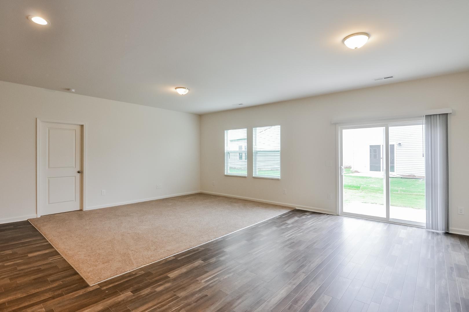 709 Kenyon Spring Drive Zebulon, NC 27597 - Photo 3 of 18 an empty room with wooden floor and windows