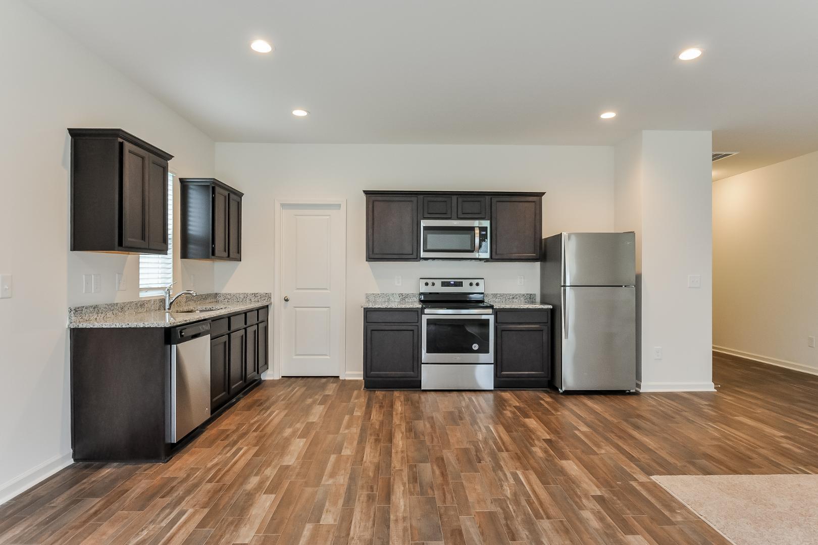 709 Kenyon Spring Drive Zebulon, NC 27597 - Photo 6 of 18 a kitchen with stainless steel appliances kitchen island granite countertop a refrigerator stove top oven and sink