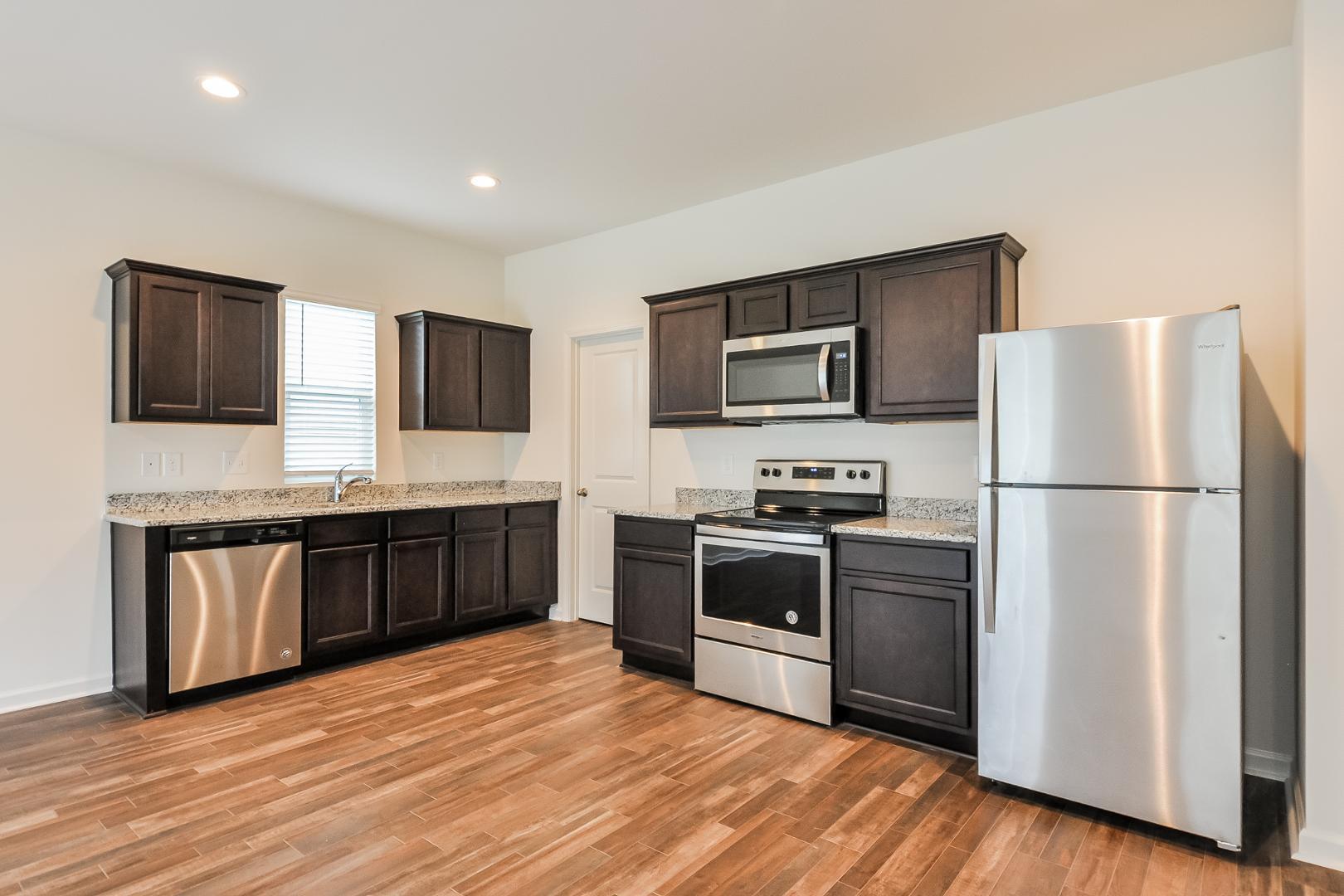 709 Kenyon Spring Drive Zebulon, NC 27597 - Photo 7 of 18 a kitchen with stainless steel appliances granite countertop a refrigerator stove a sink dishwasher and microwave with wooden floor