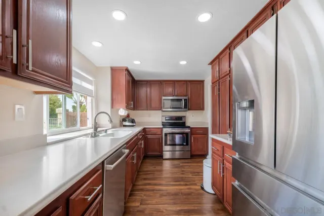 a kitchen with stainless steel appliances granite countertop refrigerator a sink a stove top oven and a refrigerator