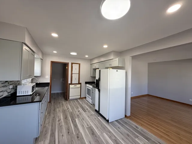 a view of a kitchen with refrigerator and wooden floor