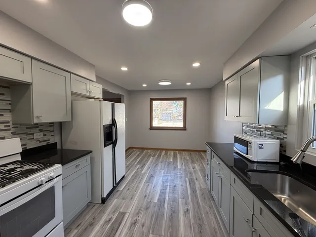 a kitchen with kitchen island granite countertop a sink stainless steel appliances and cabinets