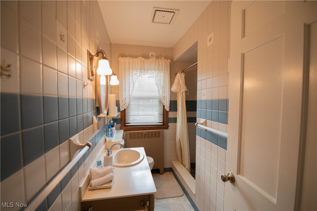 1118 Shields Road Youngstown, OH 44511 - Photo 14 of 21 Bathroom featuring tile walls, radiator, vanity, and a shower with shower curtain