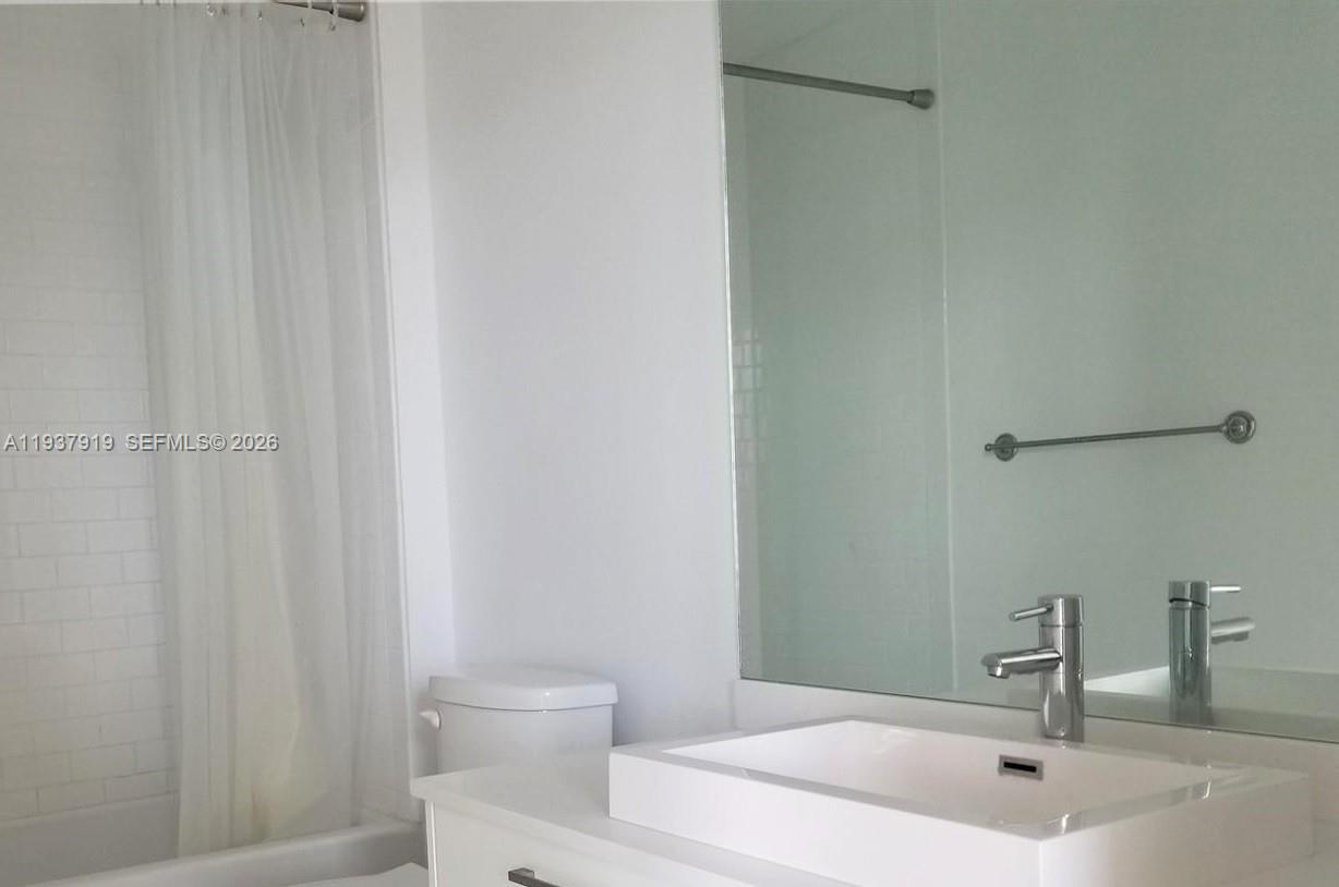 151 Southeast 1st Street, Unit 2507 Miami, FL 33131 - Photo 5 of 34 a bathroom with a sink a toilet and shower