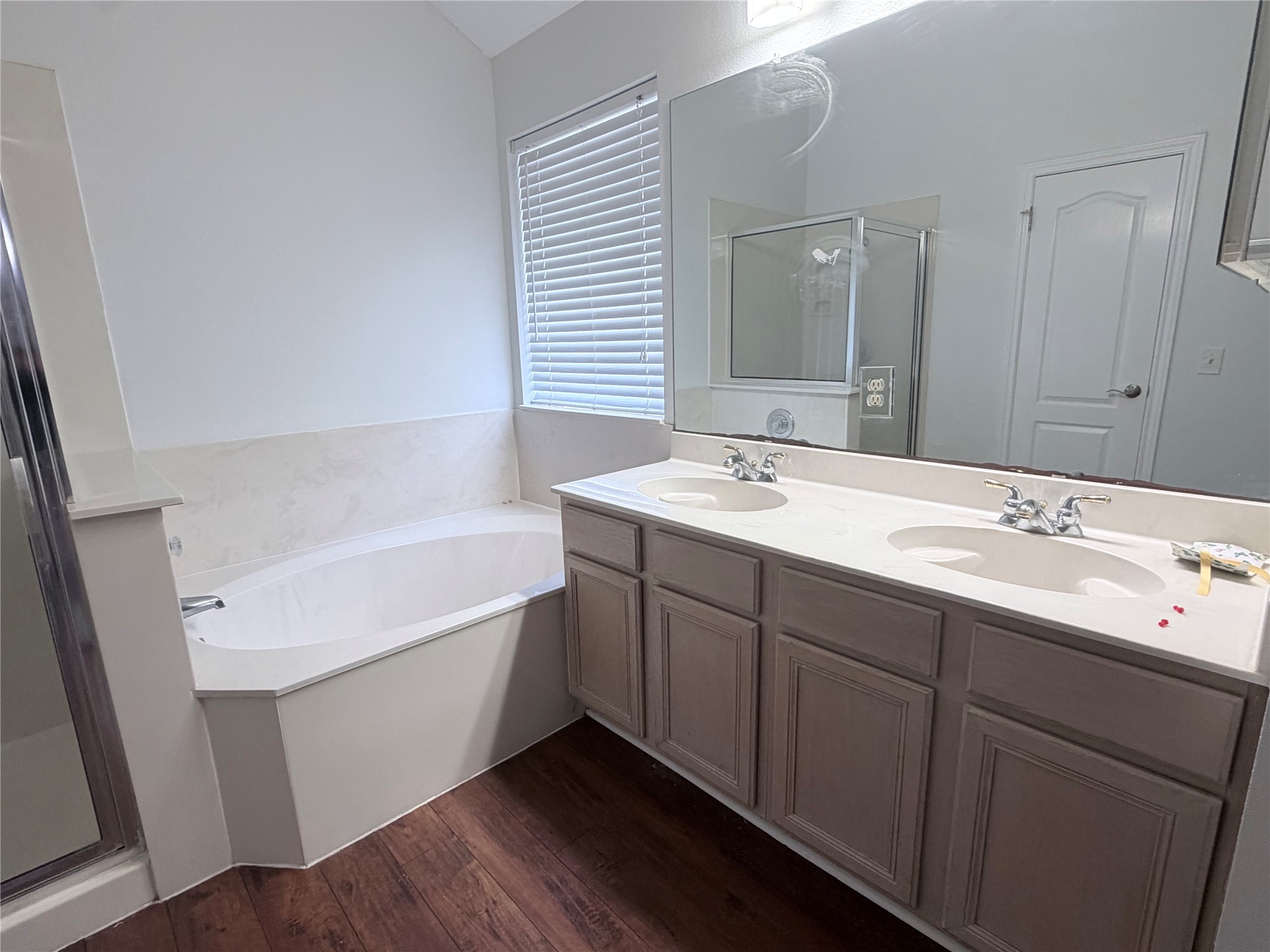 20809 Pacers Gait Lane Pflugerville, TX 78660 - Photo 14 of 23 Full bath featuring double vanity, a shower stall, a bath, and dark wood-style floors