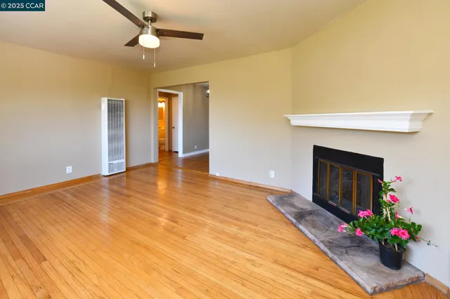 a view of empty room with wooden floor and fireplace