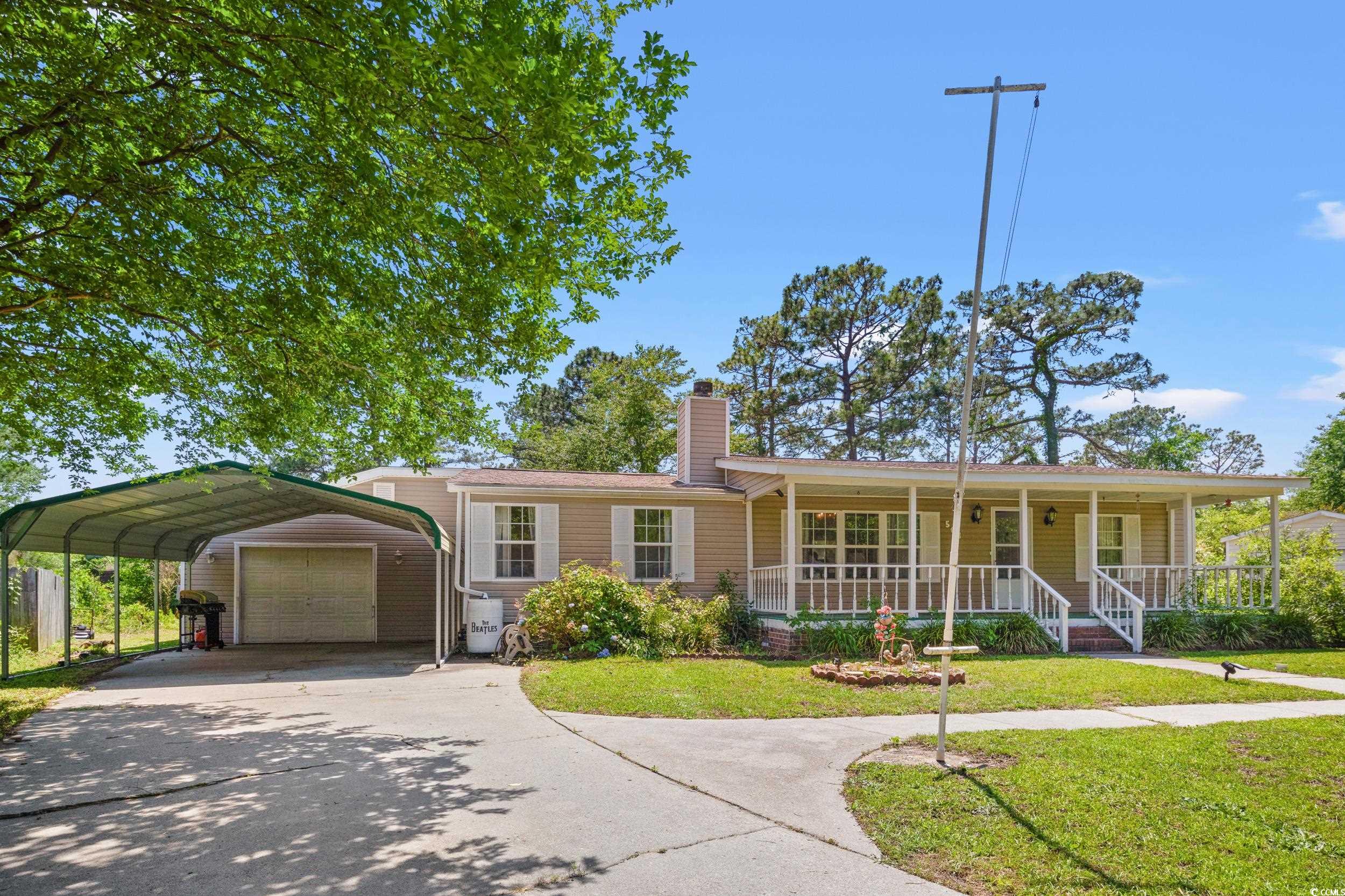 Ranch-style house featuring covered porch, a front lawn, a chimney, a garage, and driveway