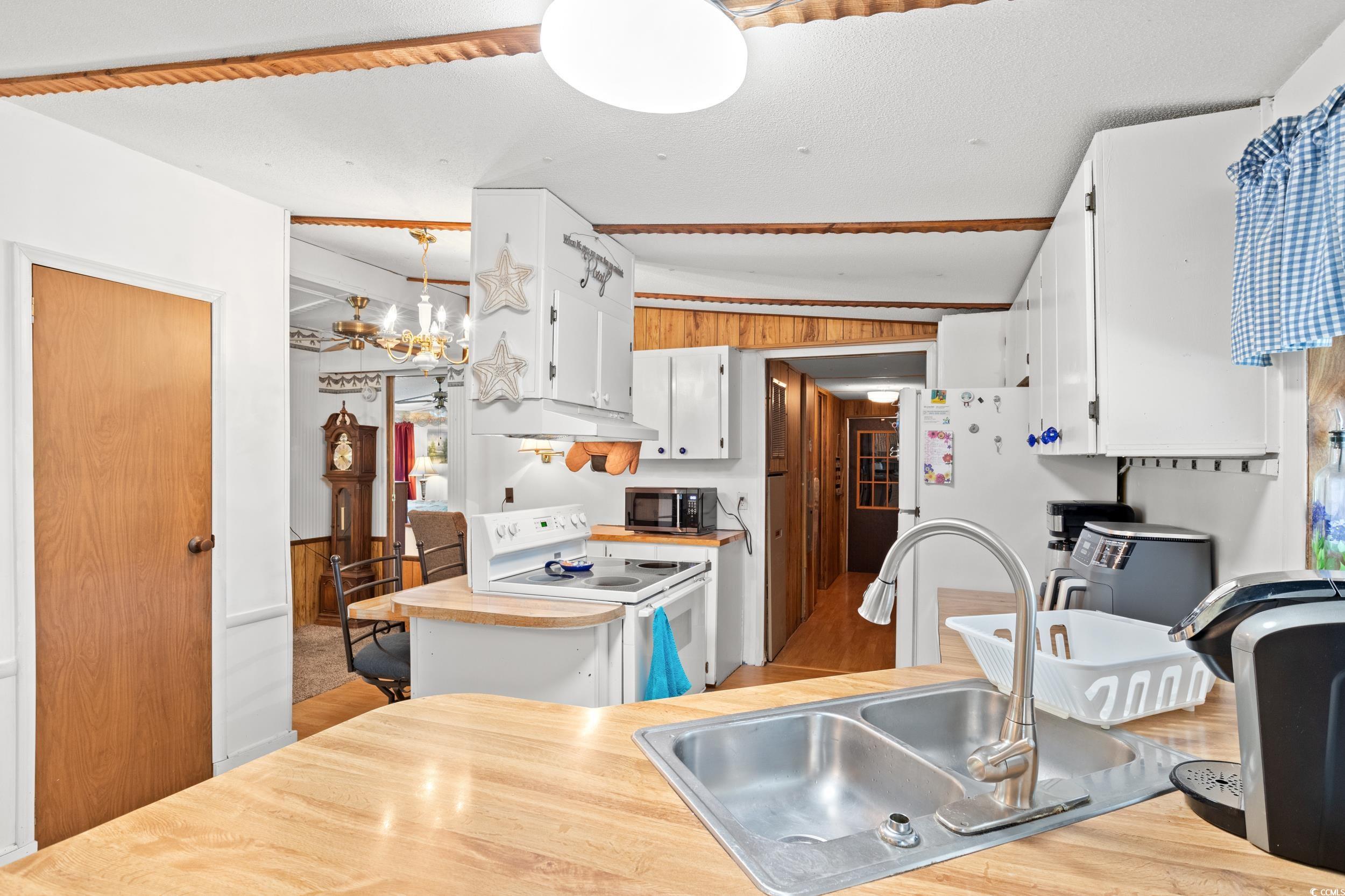 563 Plum Court Myrtle Beach, SC 29579 - Photo 15 of 34 Kitchen with white appliances, a sink, white cabinetry, a chandelier, and lofted ceiling