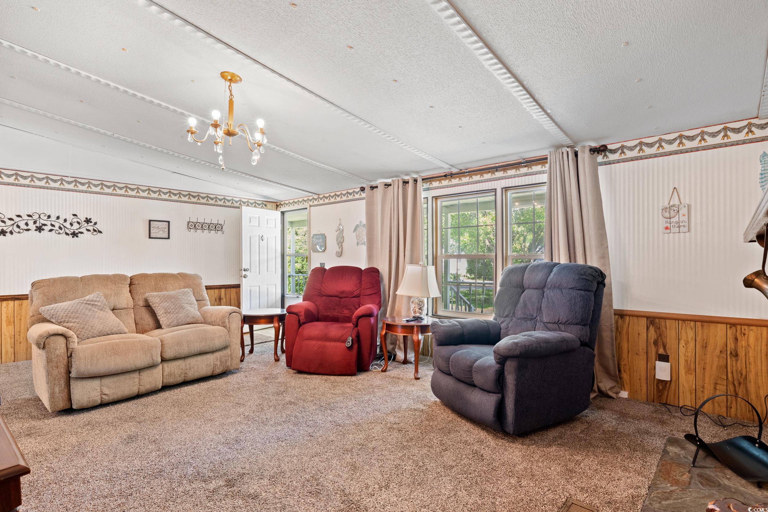 563 Plum Court Myrtle Beach, SC 29579 - Photo 18 of 34 Living area with wainscoting, carpet flooring, wood walls, vaulted ceiling, and a chandelier
