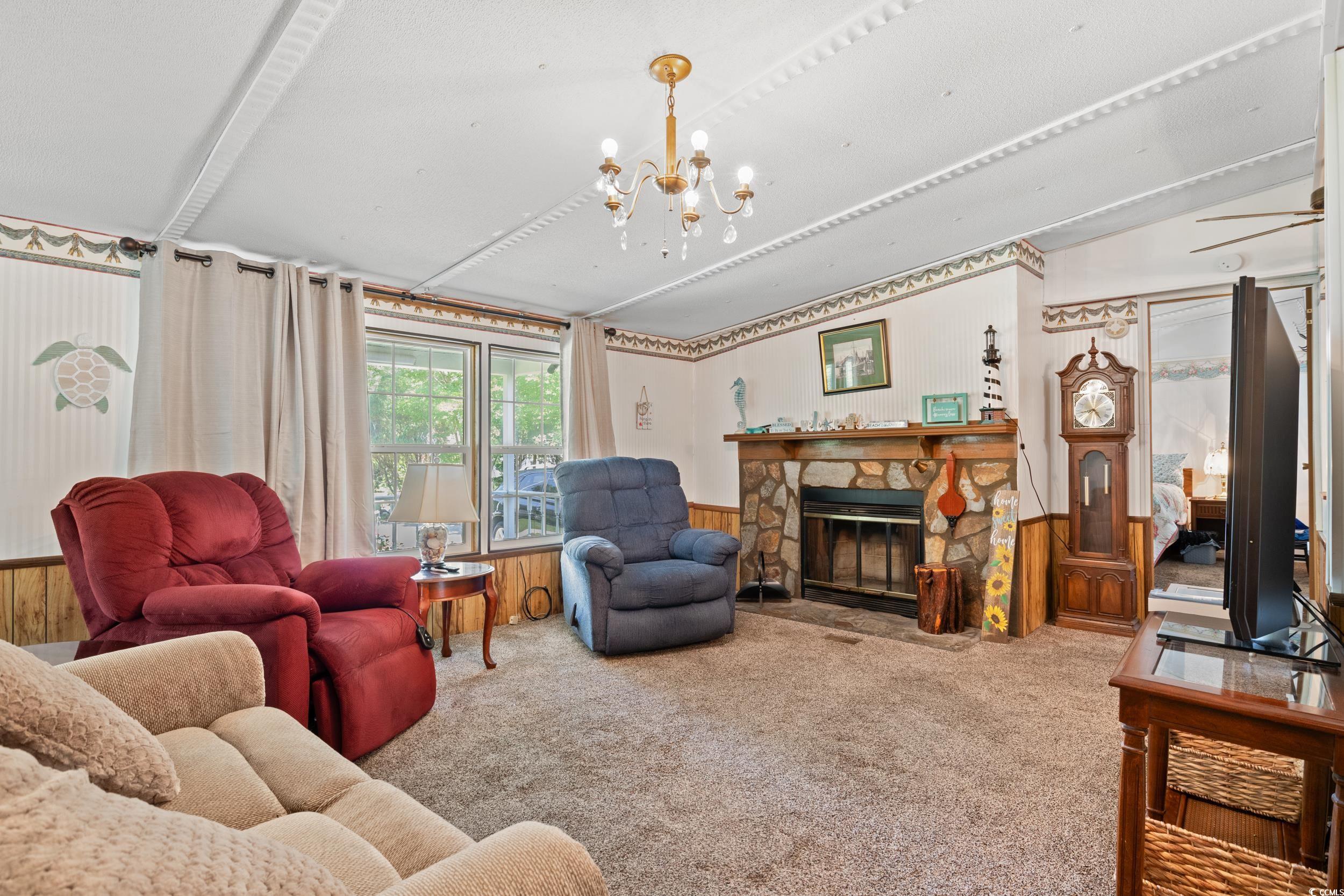 563 Plum Court Myrtle Beach, SC 29579 - Photo 20 of 34 Carpeted living area with a chandelier, a fireplace, and a wainscoted wall