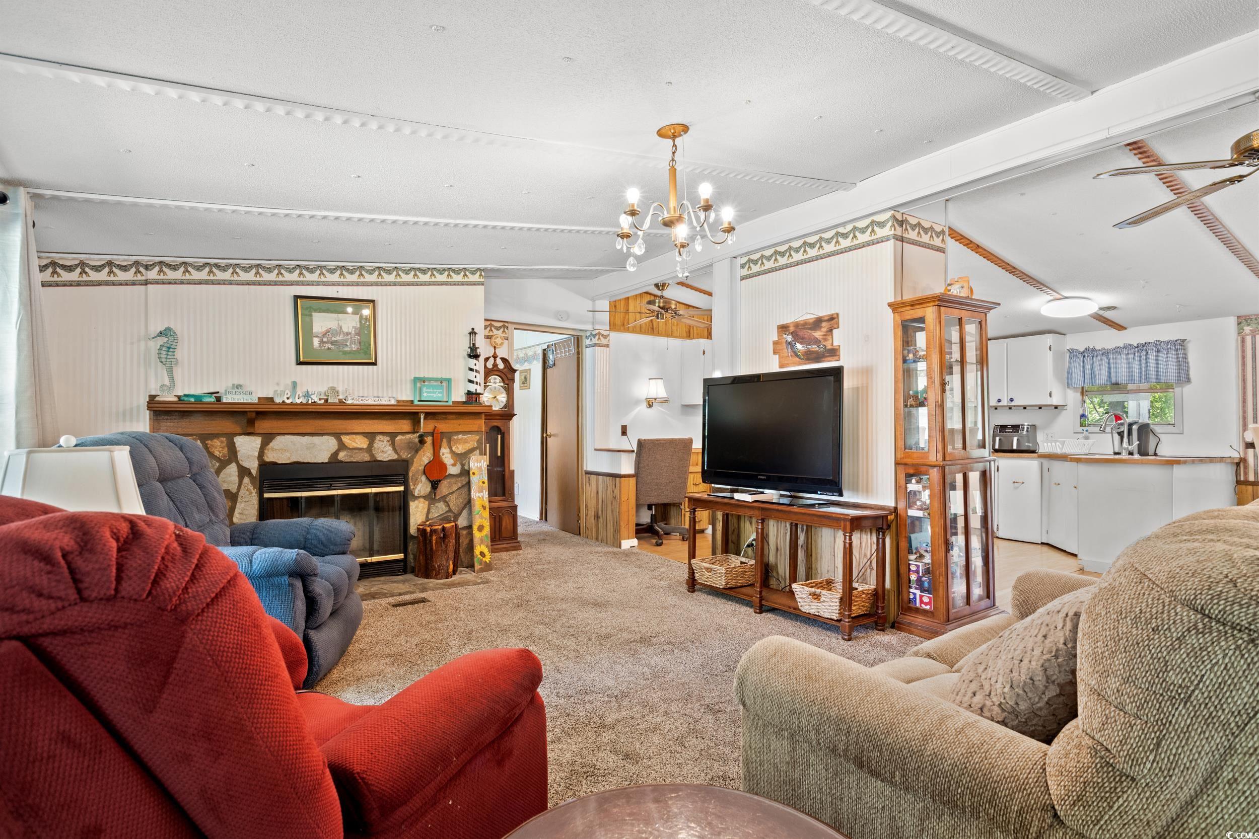 563 Plum Court Myrtle Beach, SC 29579 - Photo 21 of 34 Carpeted living room featuring a chandelier and a stone fireplace