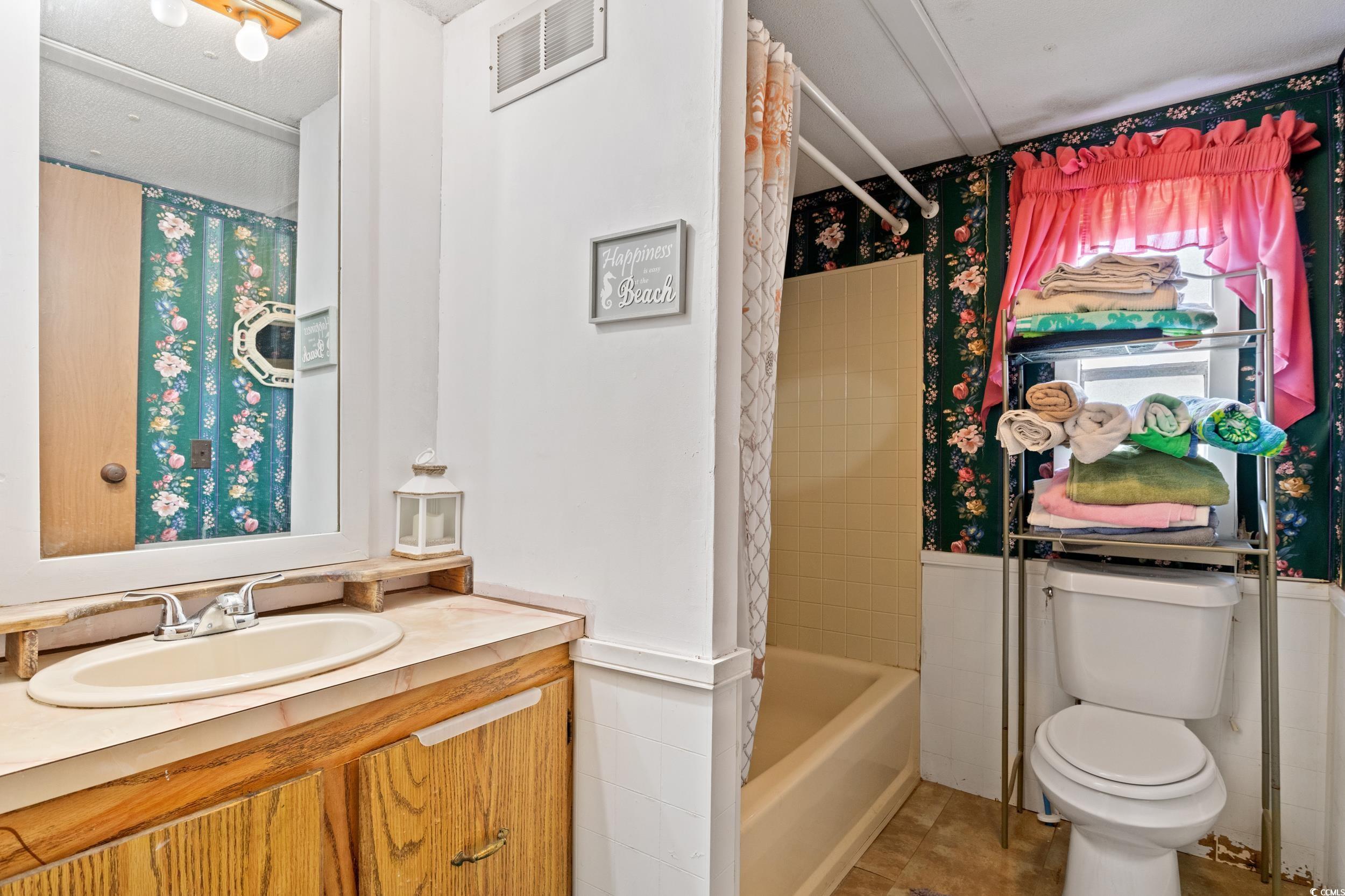 563 Plum Court Myrtle Beach, SC 29579 - Photo 7 of 34 Bathroom with toilet, vanity, tile patterned floors, wallpapered walls, and shower / bath combo with shower curtain