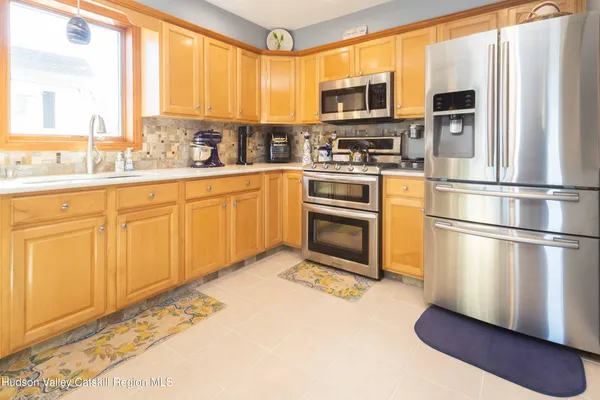 a kitchen with stainless steel appliances granite countertop a refrigerator a stove a sink and a window
