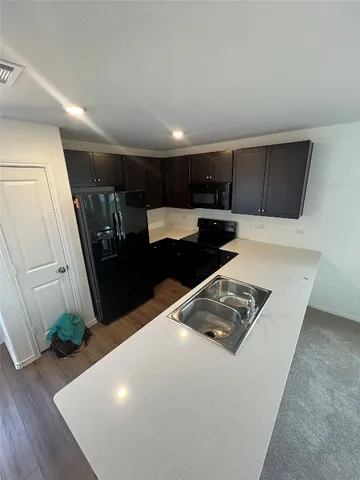 a kitchen with stainless steel appliances a refrigerator a sink a stove a microwave a counter top and oven with wooden floor