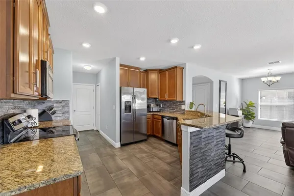 a kitchen with stainless steel appliances granite countertop a refrigerator a stove and a sink with wooden floor