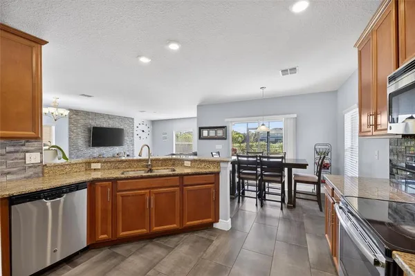 a kitchen with stainless steel appliances granite countertop stove top oven a sink dishwasher a dining table and chairs with wooden floor