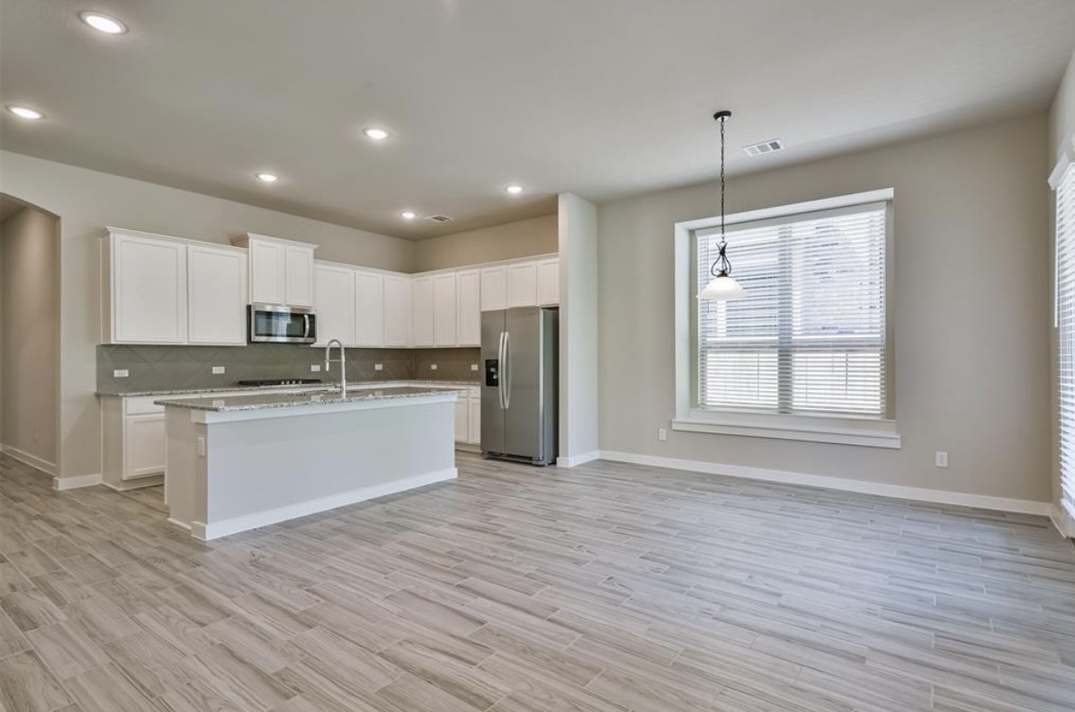 10005 Red Beadtree Place Conroe, TX 77385 - Photo 11 of 29 a kitchen with stainless steel appliances granite countertop a refrigerator a sink dishwasher a stove and white countertops with wooden floor