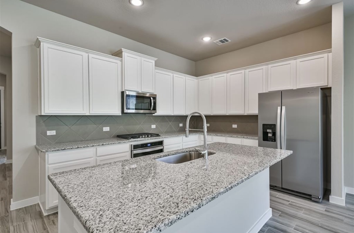 10005 Red Beadtree Place Conroe, TX 77385 - Photo 12 of 29 a kitchen with stainless steel appliances granite countertop a sink stove and refrigerator