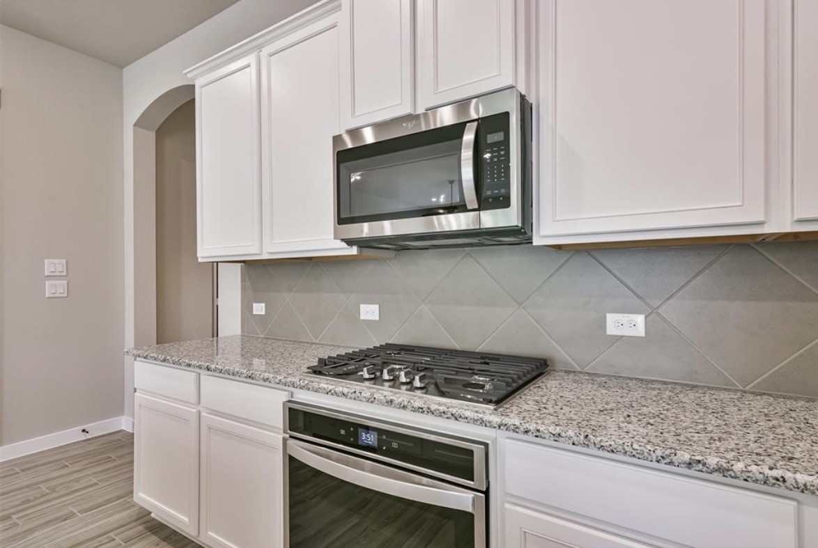 10005 Red Beadtree Place Conroe, TX 77385 - Photo 13 of 29 a kitchen with stainless steel appliances granite countertop white cabinets and a stove a oven with white countertops