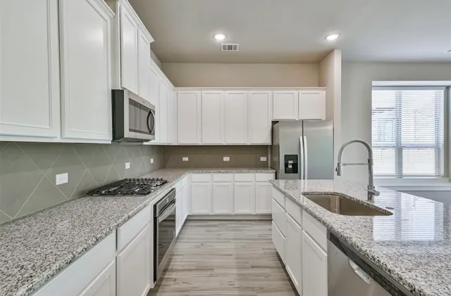 a kitchen with granite countertop a sink a stove and cabinets