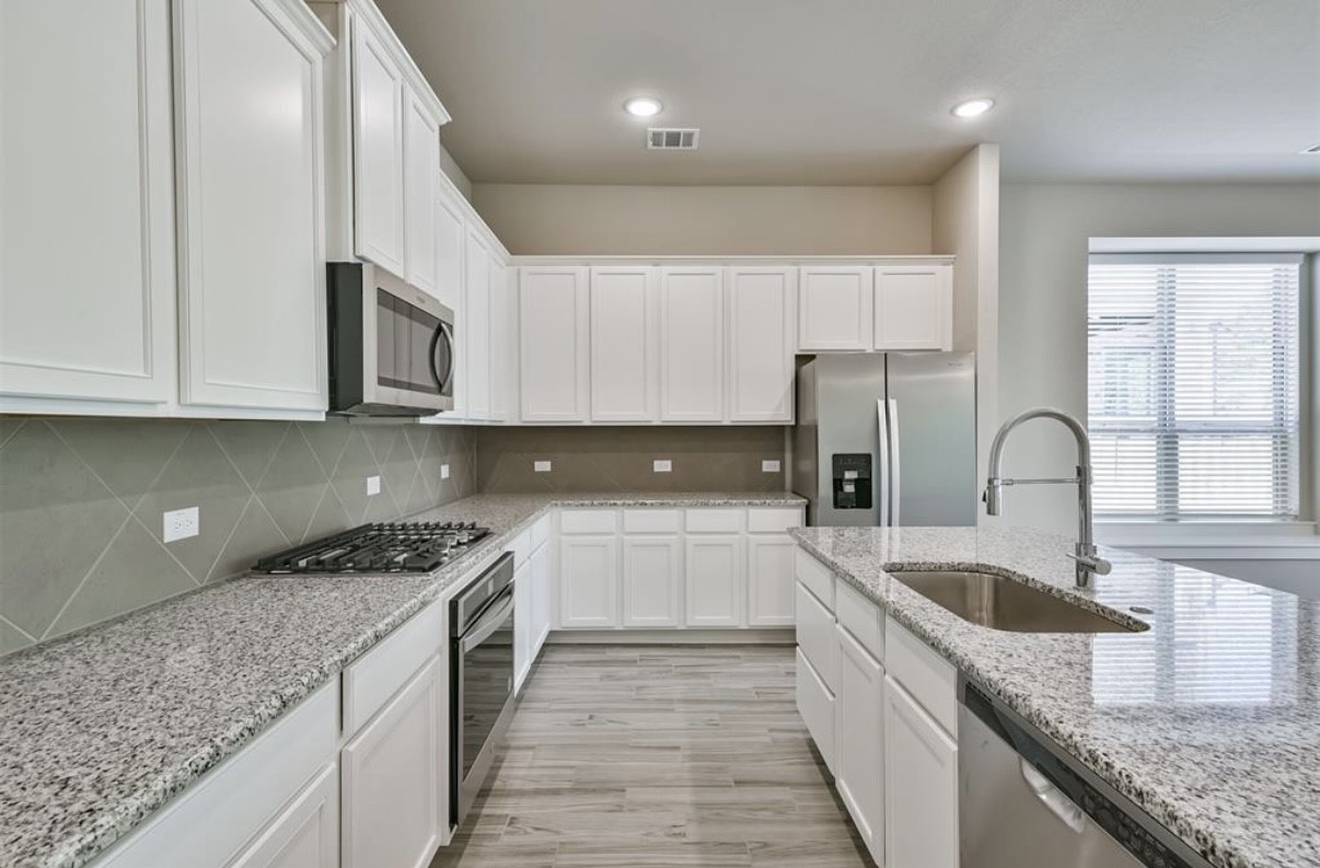 10005 Red Beadtree Place Conroe, TX 77385 - Photo 14 of 29 a kitchen with granite countertop a sink a stove and cabinets