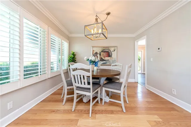 a dining room with wooden floor a chandelier a wooden table and chairs