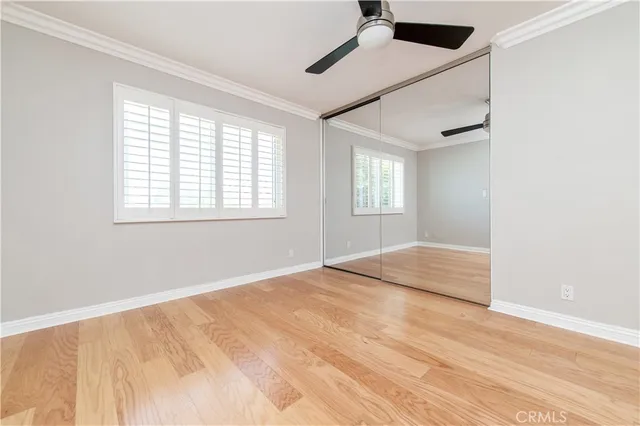 a view of empty room with wooden floor and fan