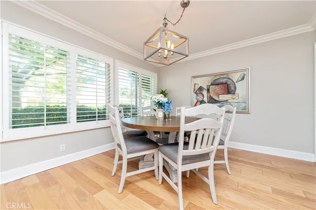 a dining room with wooden floor a chandelier a wooden table and chairs