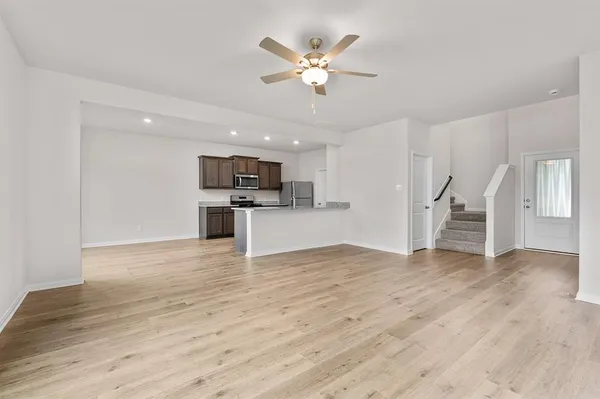 a view of an empty room with wooden floor and a ceiling fan
