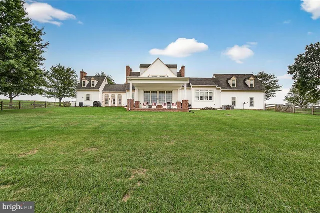 a view of a dining room and livingroom with furniture wooden floor a rug and a chandelier