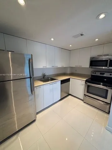 a kitchen with a refrigerator sink and cabinets