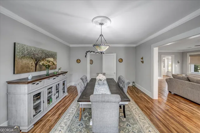 a dining room with wooden floor a chandelier a wooden table and chairs