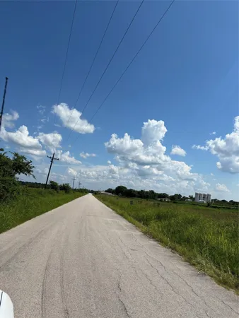 a view of a pathway both side of grassy field with shrub