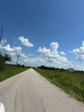 a view of a pathway both side of grassy field with shrub