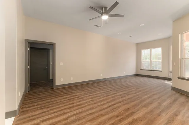 an empty room with wooden floor cabinet and windows