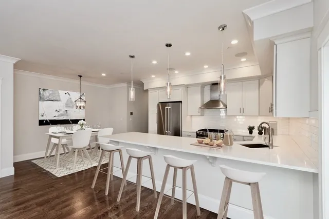 a kitchen with stainless steel appliances kitchen island granite countertop a kitchen island hardwood floor and a sink
