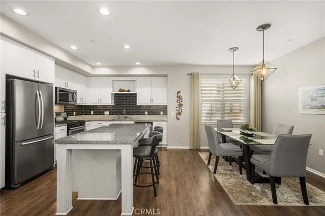 a kitchen with a dining table chairs refrigerator and microwave