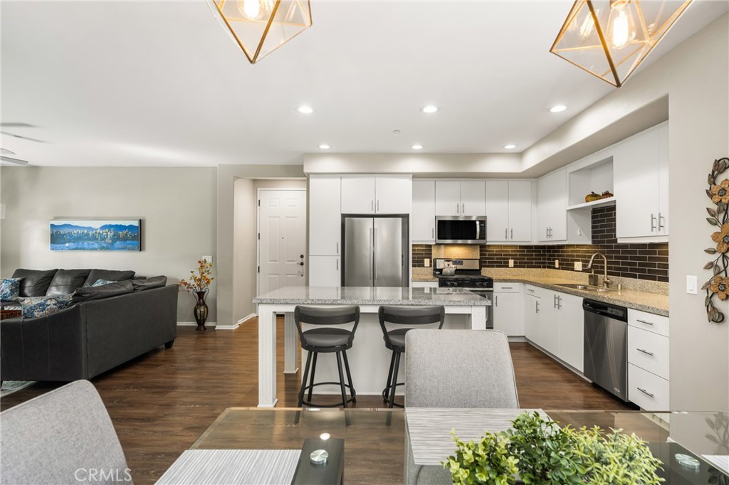 425 South Anaheim Boulevard, Unit 3 Anaheim, CA 92805 - Photo 35 of 53 a kitchen with stainless steel appliances kitchen island granite countertop a refrigerator oven a stove a sink a dining table and chairs with wooden floor
